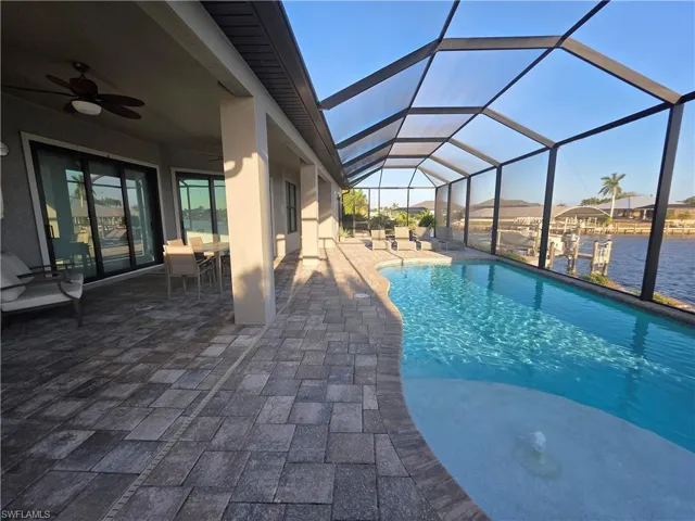 Swimming pool featuring a sunroom, a patio area, outdoor dining space, and a lanai