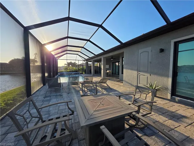 View of patio featuring a sunroom, glass enclosure, a pool with connected hot tub, and a ceiling fan