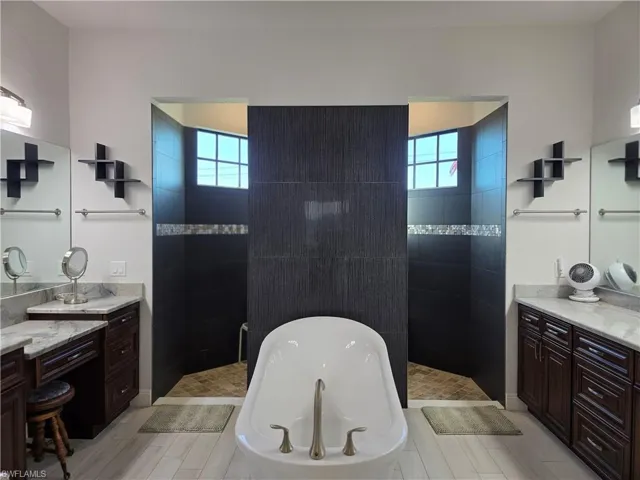 Bathroom with walk in shower, vanity, a freestanding tub, and healthy amount of natural light