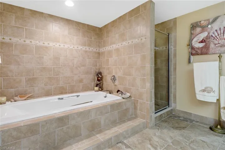 Bathroom with tile walls, tile patterned floors, and separate shower and tub
