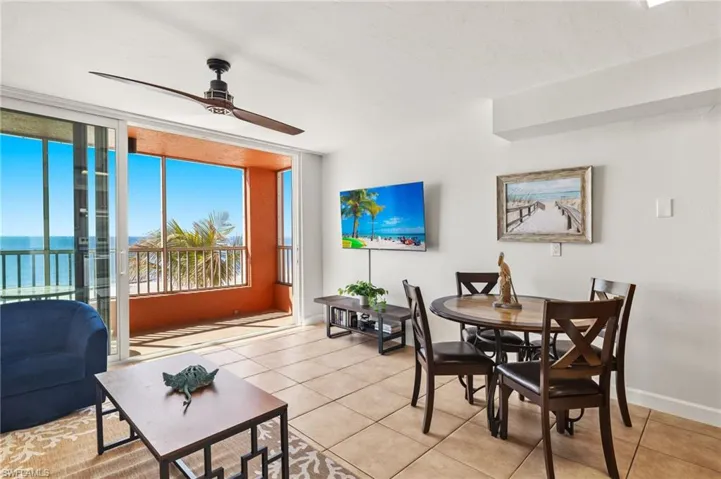 Dining space featuring a wall of windows, a water view, ceiling fan, and light tile patterned flooring