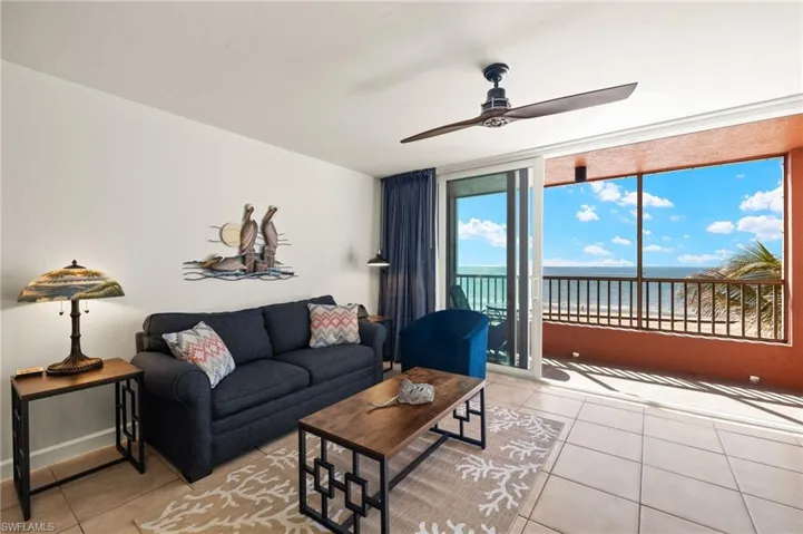 Living room with light tile patterned floors, ceiling fan, and a water view