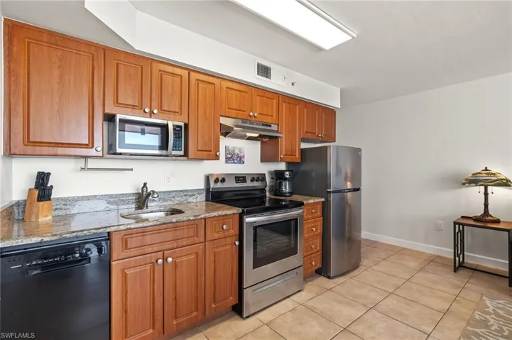 Kitchen featuring light stone counters, appliances with stainless steel finishes, sink, and light tile patterned floors