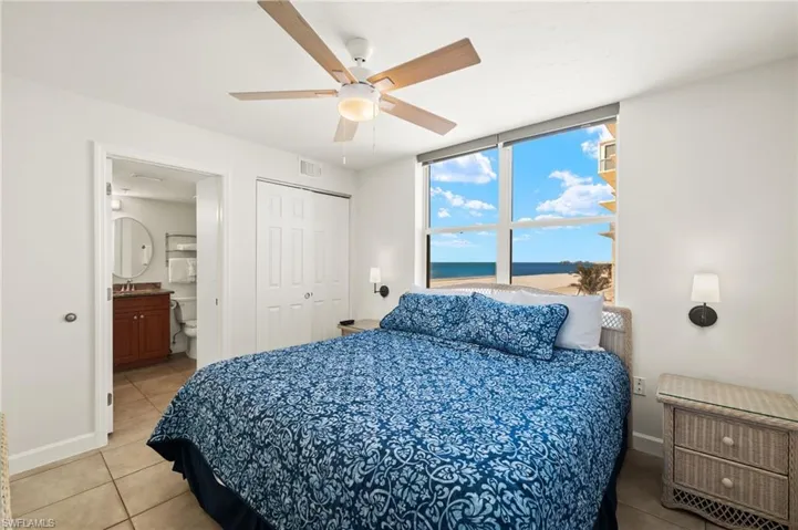 Tiled bedroom featuring ceiling fan, ensuite bath, sink, and a closet