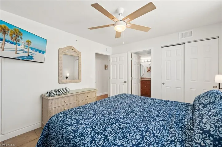 Bedroom featuring tile patterned flooring, connected bathroom, a closet, and ceiling fan