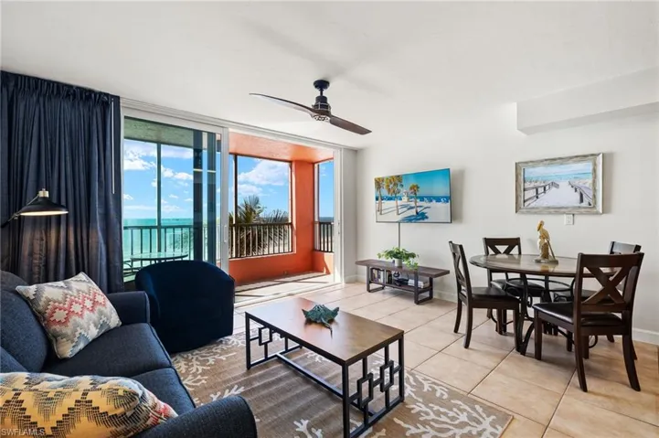 Tiled living room with ceiling fan and a wall of windows