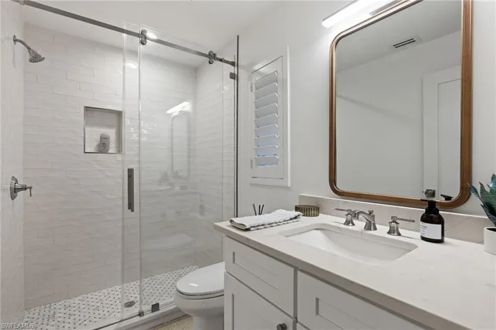 Bathroom with an enclosed shower, vanity, and toilet