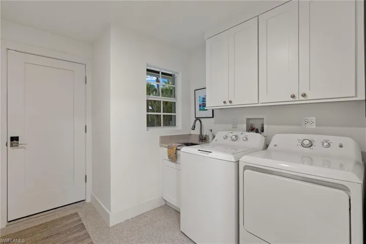 Laundry area with washer and clothes dryer, cabinets, and sink