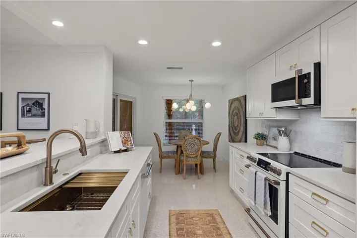 Kitchen featuring white cabinets, a chandelier, electric range, and sink