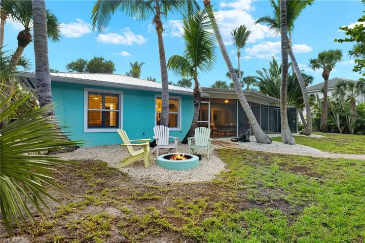 Back of property featuring a sunroom, an outdoor fire pit, and a patio area