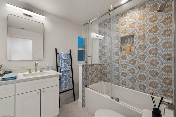 Full bathroom featuring enclosed tub / shower combo, vanity, and toilet