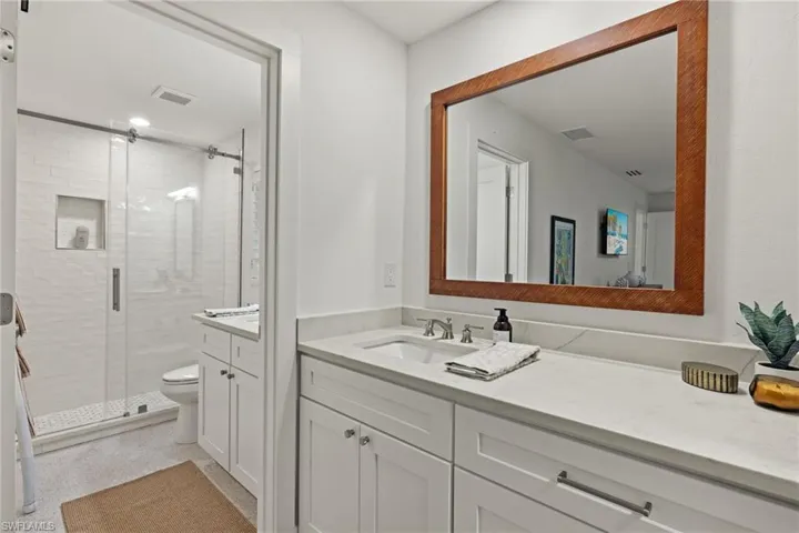 Bathroom featuring vanity, toilet, and a shower with door