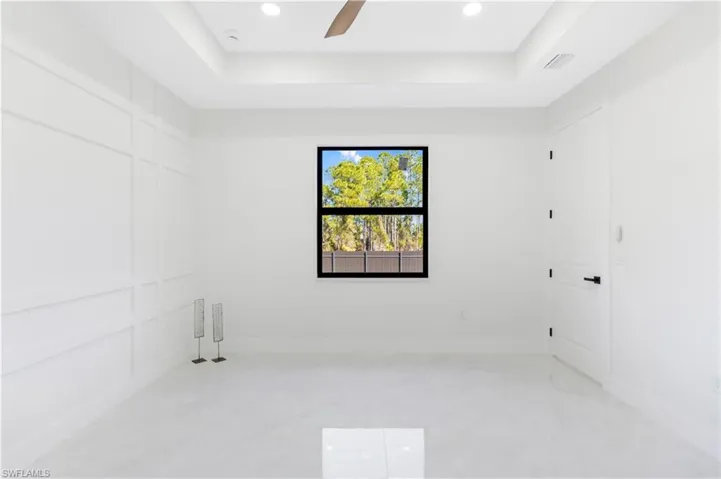 Unfurnished room featuring a tray ceiling, a ceiling fan, a decorative wall, and recessed lighting