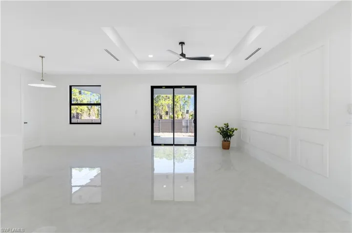 Living room with plenty of natural light, a tray ceiling, ceiling fan, and recessed lighting