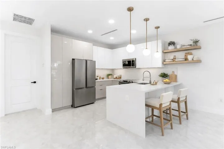 Virtually Staged Kitchen featuring white cabinetry, a peninsula, a kitchen breakfast bar, modern cabinets, and decorative light fixtures