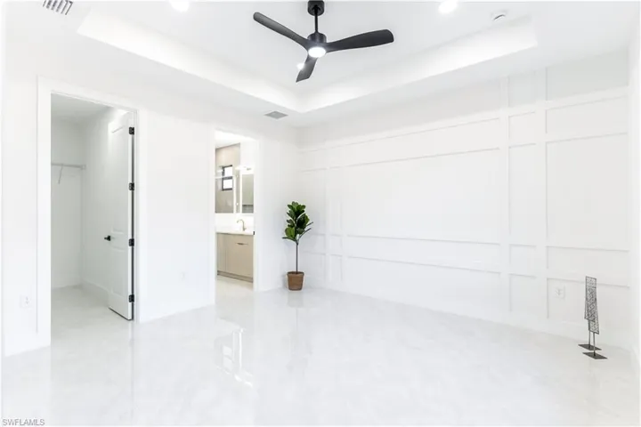 Empty room featuring ceiling fan and a raised ceiling