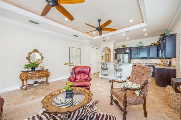 Tiled living room featuring ornamental molding, ceiling fan, and a tray ceiling