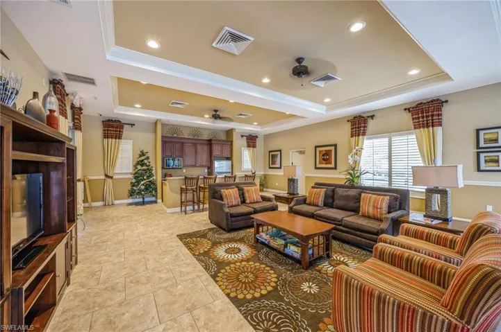 Tiled living room with a raised ceiling, crown molding, and ceiling fan