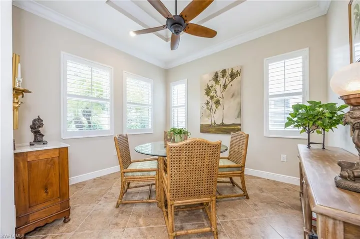 Tiled dining space featuring ornamental molding and ceiling fan