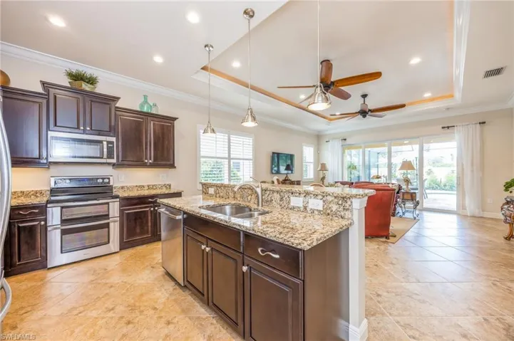 Kitchen featuring ornamental molding, appliances with stainless steel finishes, sink, and a tray ceiling