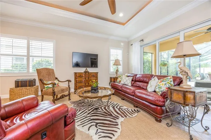 Living room featuring ceiling fan, a raised ceiling, and crown molding