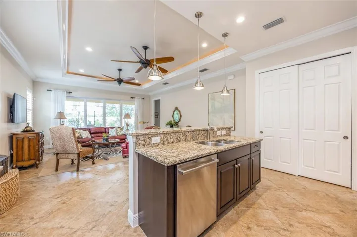 Kitchen with sink, pendant lighting, dishwasher, ceiling fan, and a raised ceiling