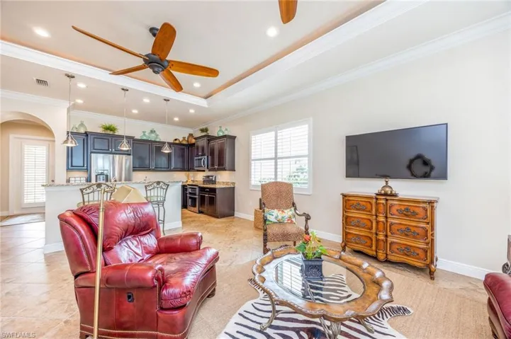 Tiled living room with a tray ceiling, crown molding, and ceiling fan