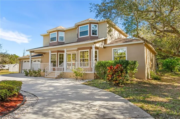 Two-story residence featuring a stucco exterior with bay windows and a covered front porch