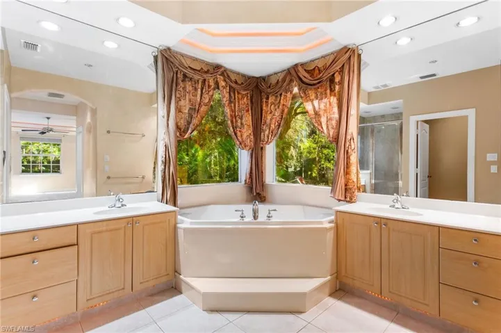 Corner soaking tub with surrounding windows and decorative drapery