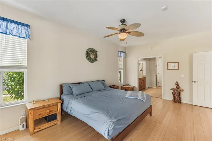 Bedroom with light wood-type flooring, ceiling fan, and ensuite bath