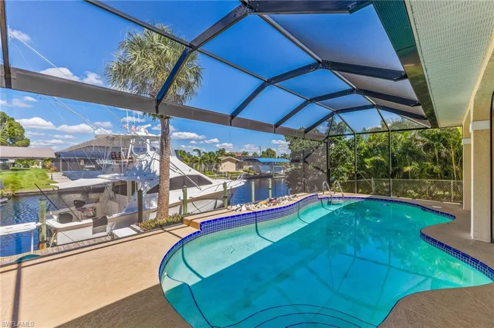 Swimming pool with boat lift, a sunroom, a water view, glass enclosure, and a dock