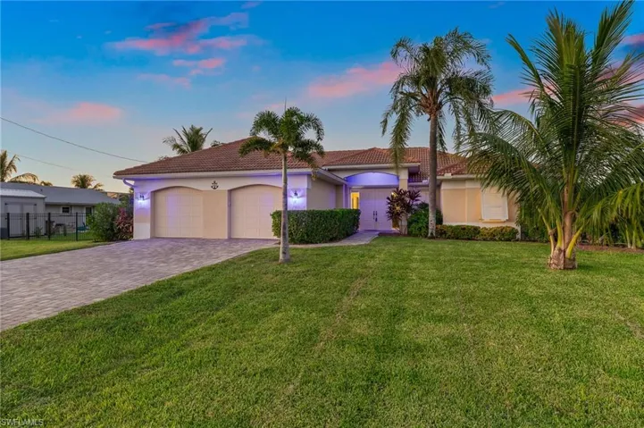 Mediterranean / spanish home with a yard, stucco siding, an attached garage, and a tile roof