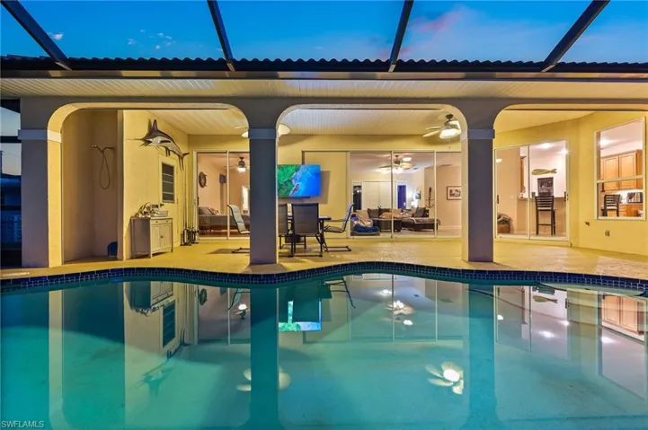 Outdoor pool with ceiling fan, glass enclosure, and a patio