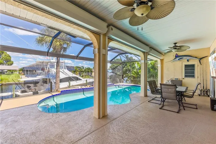 Swimming pool with ceiling fan, a sunroom, a patio area, a lanai, and outdoor dining area
