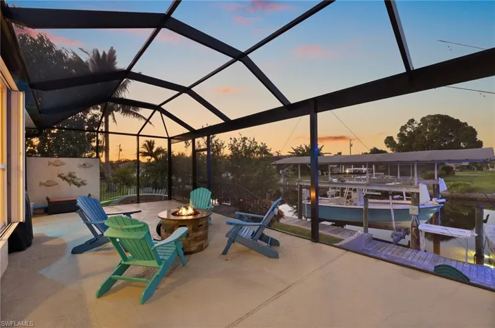 Patio terrace at dusk featuring a dock, boat lift, glass enclosure, and a sunroom