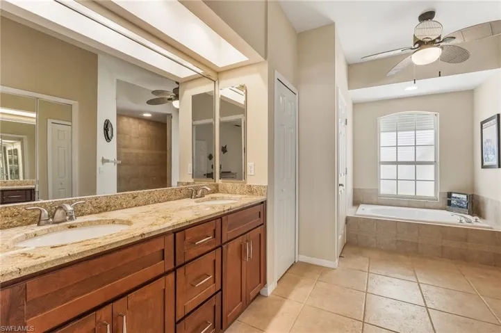 Full bathroom with ceiling fan, a closet, double vanity, light tile patterned flooring, and a bath