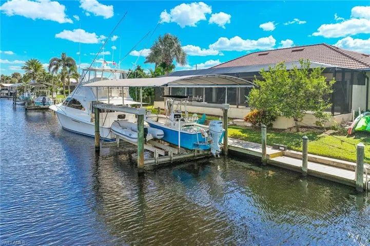 Dock area featuring boat lift, a lanai, a water view, and a sunroom