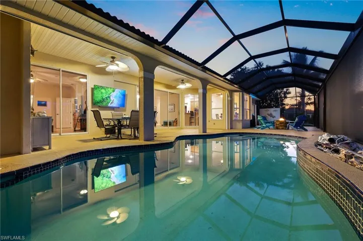 Indoor pool with a sunroom, a patio area, a ceiling fan, glass enclosure, and outdoor dining area