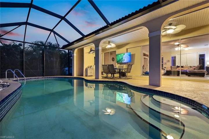 Swimming pool featuring ceiling fan, a patio area, glass enclosure, a sunroom, and outdoor dining space