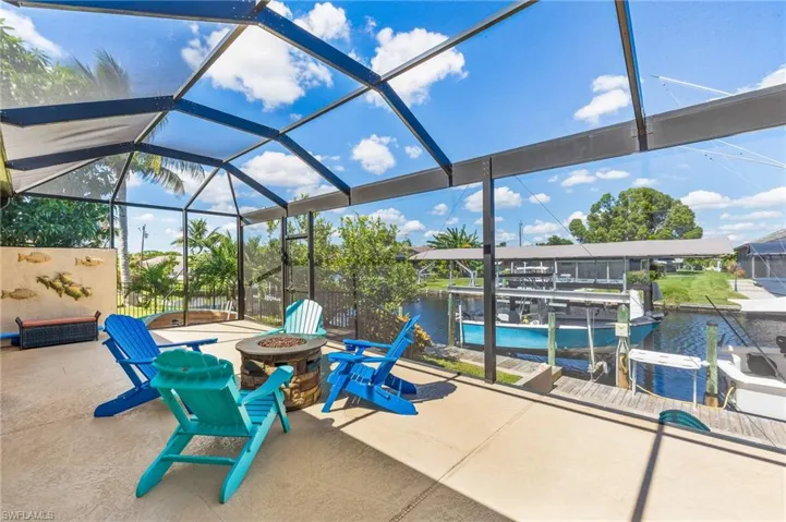 View of patio / terrace with a sunroom, boat lift, a water view, a lanai, and an outdoor fire pit