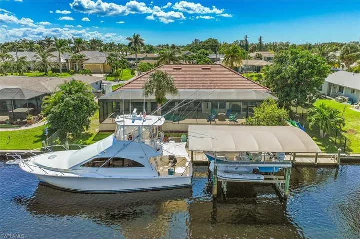 Dock area with a residential view, boat lift, a water view, and a lanai