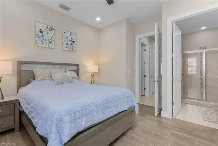 Bedroom with wood tiled floors, a ceiling fan, ensuite bath, and recessed lighting
