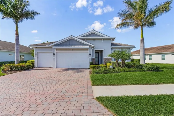 View of front of house featuring a front yard, 3 car garage, paver driveway