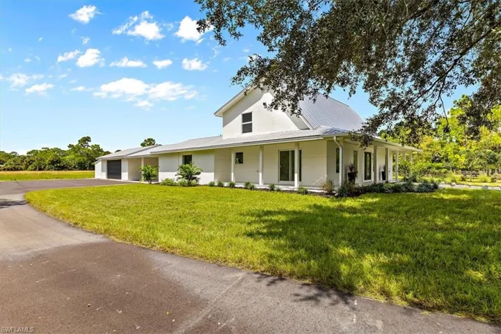 Farmhouse-style home featuring covered porch, a front yard, and a garage