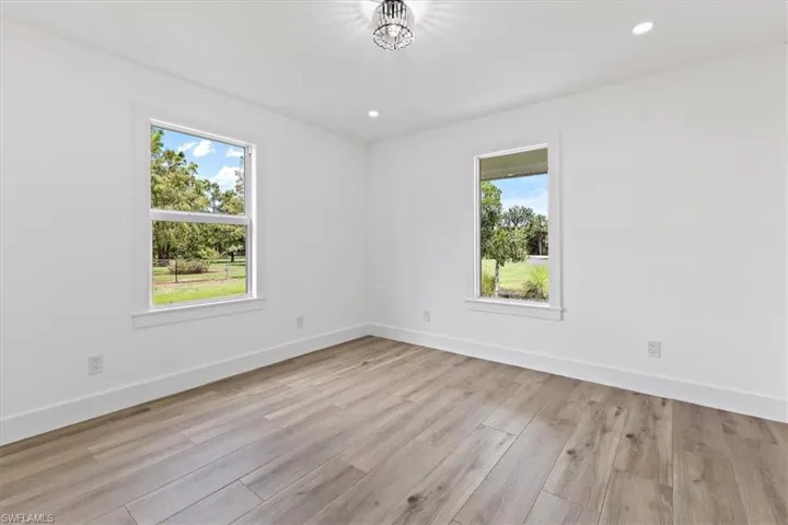 Empty room featuring light wood-type flooring and an inviting chandelier