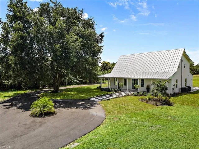 View of front of home featuring covered porch, central AC unit, and a front lawn