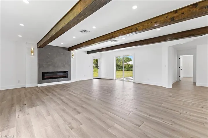 Unfurnished living room featuring light hardwood / wood-style flooring, beamed ceiling, and a fireplace