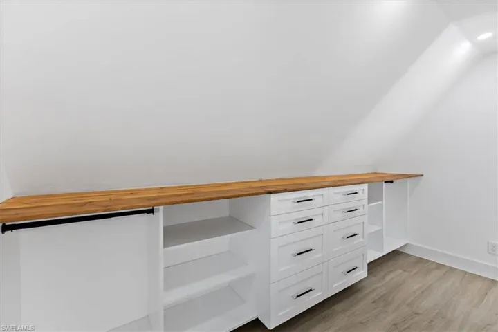 Walk in closet with light hardwood / wood-style floors