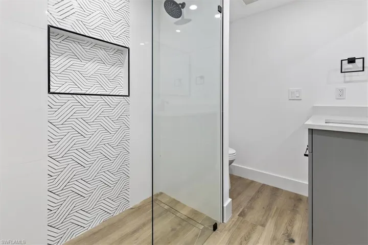 Bathroom featuring vanity, toilet, wood-type flooring, and walk in shower