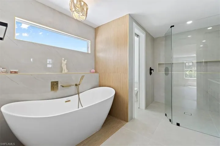 Bathroom with tile walls, separate shower and tub, toilet, and tile patterned floors